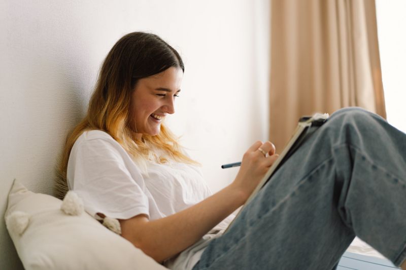 A teenage girl is drawing or doing homework in the bedroom. A teenager studies at home. Back to school