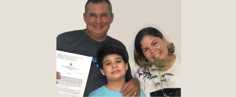 Arthur Gabriel e os pais, Eduardo e Fabrina, mostram o Habeas Corpus e um pé de Cannabis autorizado pela Justiça (Arquivo Pessoal)