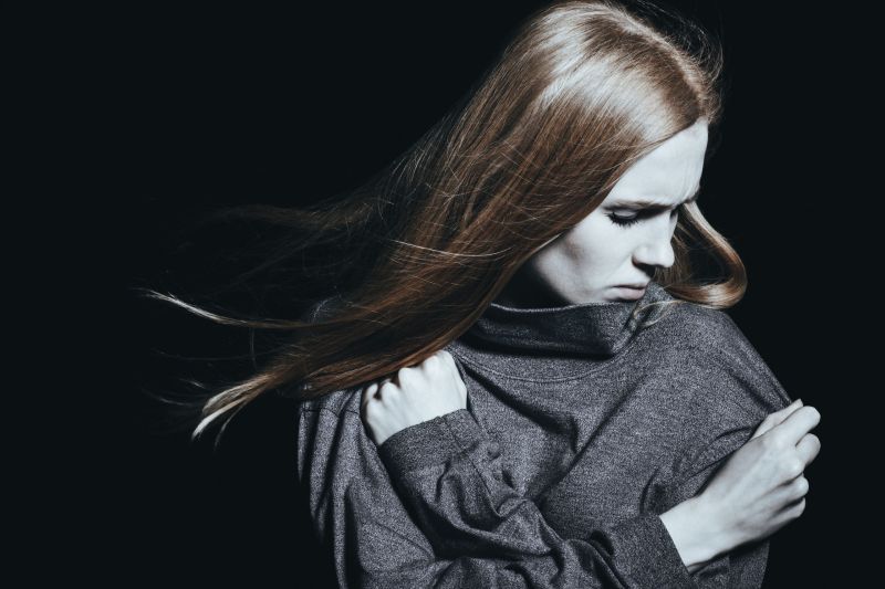 Depressed woman with mental disorder against black background